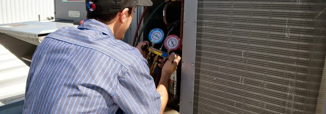 HVAC technician servicing a condenser unit in Derry