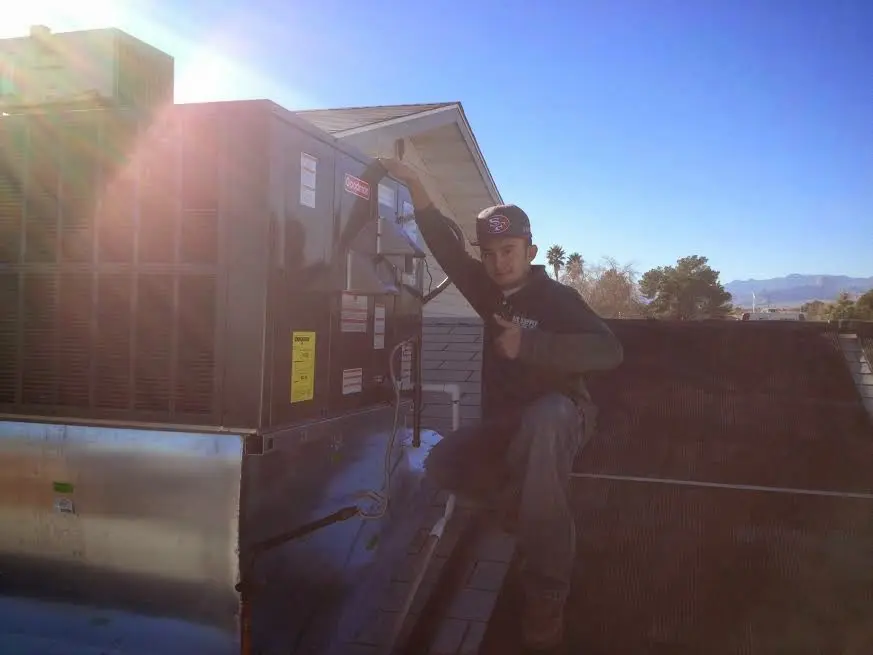 HVAC technician performing AC Tune-Up on a rooftop unit in Derry